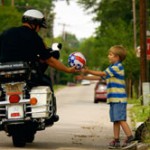 Police officer handing ball to child